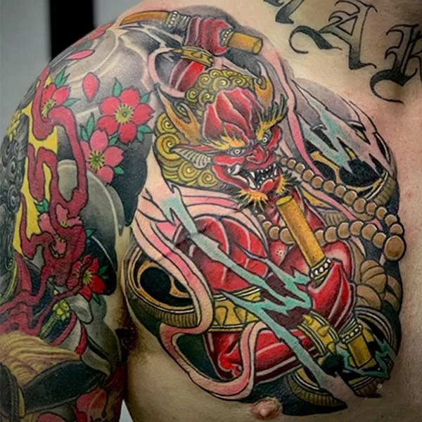 Gợi ý 70+ hình xăm Thần sấm Raijin cực ngầu và chất 32 Hình xăm nghệ thuật trên vai và ngực với hình ảnh quái thú đỏ, hoa và các chi tiết trang trí phức tạp.