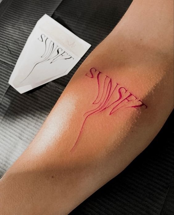 Mini tattoo chữ màu đỏ ở bắp tay