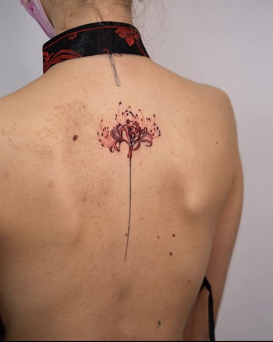 H&igrave;nh xăm hoa m&agrave;u đỏ tr&ecirc;n lưng người đang mặc trang phục cổ cao, nền trắng.