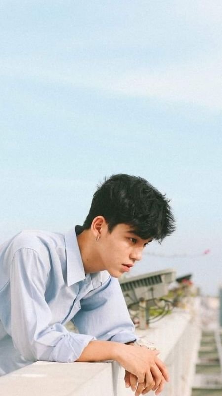 Người đứng tựa vào lan can, nhìn xa xăm, trời trong xanh.