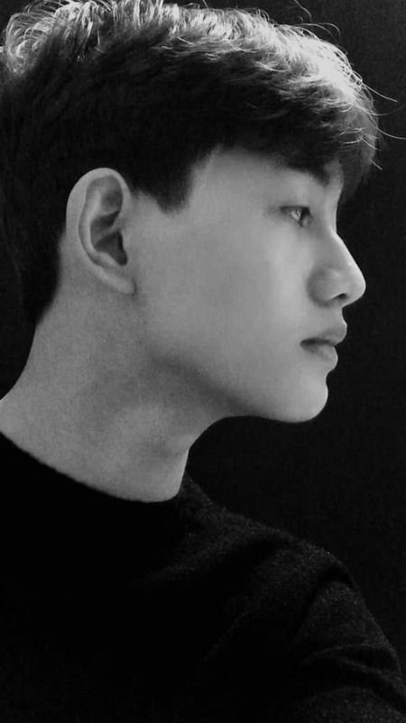 Chân dung nghiêng của một người trong ánh sáng đen trắng, nhìn về phía xa với vẻ mặt điềm tĩnh.